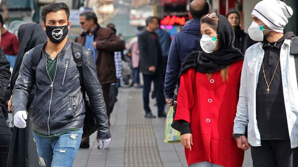 A man wears a protective mask bearing the logo of the US' National Aeronautics and Space Administration (NASA) while walking with others also wearing masks along a street in the Iranian capital Tehran on February 24, 2020 - Sputnik International