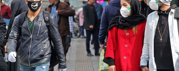 A man wears a protective mask bearing the logo of the US' National Aeronautics and Space Administration (NASA) while walking with others also wearing masks along a street in the Iranian capital Tehran on February 24, 2020 - Sputnik International