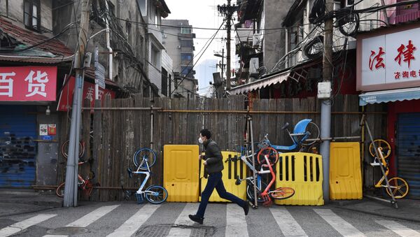 A man wearing a face mask runs past a street blocked by barricades and shared bicycles in Wuhan, the epicentre of the novel coronavirus outbreak, Hubei province, China March 5, 2020 - Sputnik International