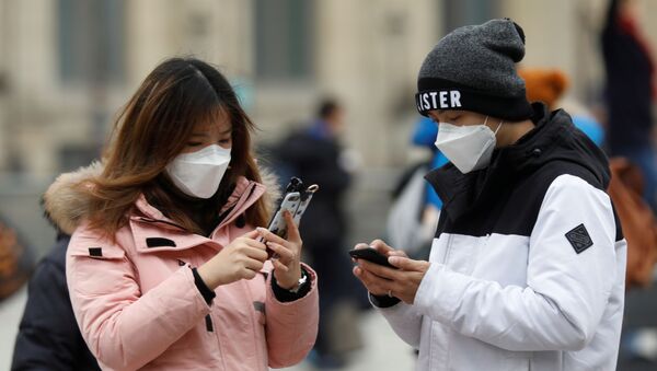 A couple wearing masks check their mobile phones - Sputnik International