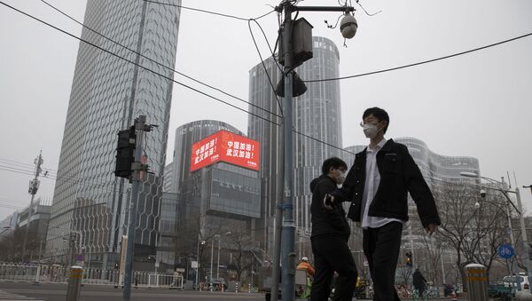Residents walk past a retail and office district with a screen showing propaganda which reads Go China! Go Wuhan as businesses slowly restart in Beijing on Sunday, March 8, 2020. As China's coronavirus cases and death steadily falls, authorities are trying to restart its businesses and factories after a virtual shutdown which has had a ripple effect affecting the global economy.  - Sputnik International
