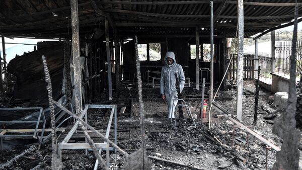 Israel from Congo, a migrant who was also a teacher of the school for refugee children walks through the burnt facilities of the school of the One Happy Family NGO's project on the island of Lesbos on March 8, 2020. - Sputnik International