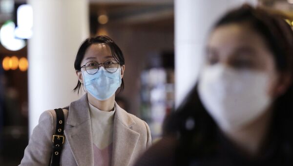 Travelers at Seattle-Tacoma International Airport wear masks Tuesday, March 3, 2020, in SeaTac, Wash. Six of the 18 Western Washington residents with the coronavirus have died as health officials rush to test more suspected cases and communities brace for spread of the disease. - Sputnik International