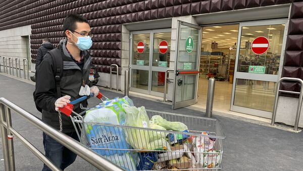 A man wearing a protective mask leaves a supermarket with trolleys full of shopping in Milan on March 8, 2020 as Italy quarantines more than 10 million people around the financial capital Milan and the tourist mecca Venice for nearly a month to halt the spread of the novel coronavirus, COVID-19. - Sputnik International