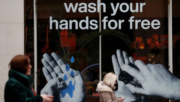 Women walk past a sign in a shop window offering a free hand washing service to customers in Liverpool - Sputnik International