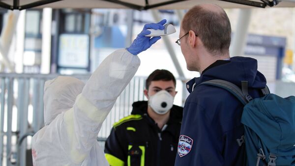 A person wearing a protective suit and mask checks the temperature of people departing from the ferry port of Molo Beverello after Italy orders a countrywide lockdown to try and contain a coronavirus outbreak, in Naples, Italy, March 10, 2020.  - Sputnik International