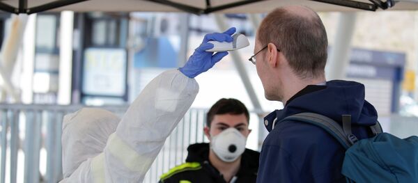 A person wearing a protective suit and mask checks the temperature of people departing from the ferry port of Molo Beverello after Italy orders a countrywide lockdown to try and contain a coronavirus outbreak, in Naples, Italy, March 10, 2020.  - Sputnik International