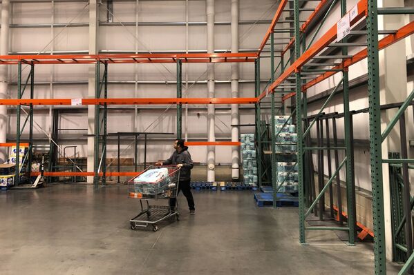 A customer walks past mostly empty shelves that normally hold toilet paper and paper towels at a Costco store in Teterboro, N.J., Monday, March 2, 2020 - Sputnik International