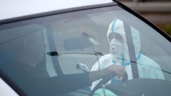 A picture taken on March 9, 2020 on the Polish side shows a medical staff taking the temperature of a driver during sanitary checks at Jedrzychowice border crossing, between Poland and Germany, in a measure to protect against the spread of the novel coronavirus. - Sputnik International