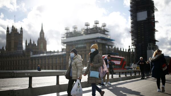 The Houses of Parliament can be seen as people wearing protective face masks walk across Westminster Bridge - Sputnik International