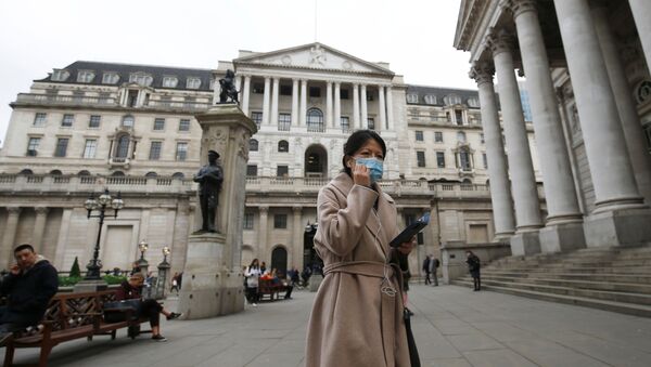 A woman, wearing a protective face mask, walks in front of the Bank of England, following an outbreak of the coronavirus, in London, Britain March 11, 2020 - Sputnik International