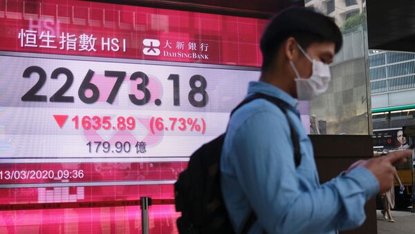 A man wears a protective mask as he walk past a panel displaying the Hang Seng Index during morning trading - Sputnik International
