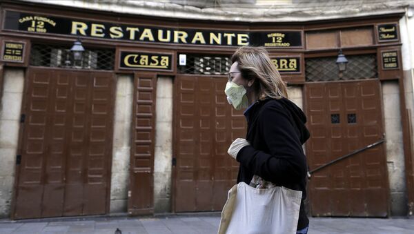 A woman wears a face mask as she walks in front of a closed restaurant in downtown Madrid, Spain, Saturday, March 14, 2020. Spanish Prime Minister Pedro Sanchez said his government will declare a two-week state of emergency on Saturday, giving itself extraordinary powers including the mobilization of the armed forces, to confront the COVID-19 outbreak. For some, especially older adults and people with existing health problems, it can cause more severe illness, including pneumonia. - Sputnik International