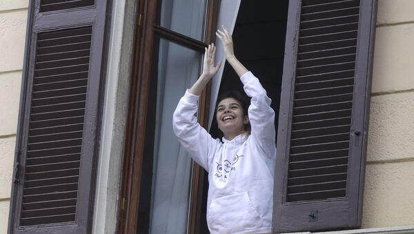 A girl leans out of a window to applaud in Milan - Sputnik International