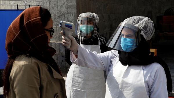Afghan health worker in protective gear checks the temperature of a woman - Sputnik International