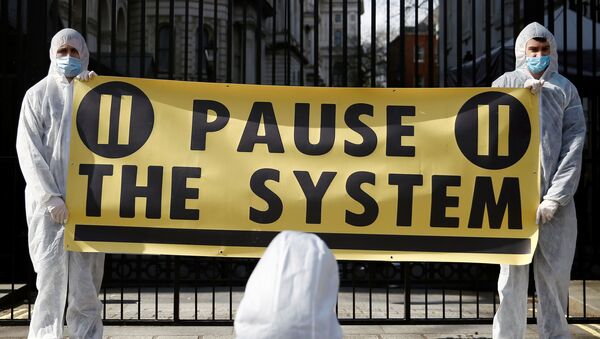 Protesters from organization Pause the System wearing hazmat suits demonstrate against government's response to the coronavirus crisis, outside Downing Street in London, Britain March 16, 2020. REUTERS/Henry Nicholls - Sputnik International