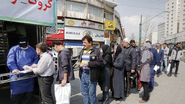 People queue in line to receive packages for precautions against COVID-19 provided by the Basij, a militia loyal to Iran's Islamic republic establishment, from a booth outside Meydane Valiasr metro station in the capital Tehran on 15 March 2020.  Iran remains one of the world's worst-affected countries. - Sputnik International