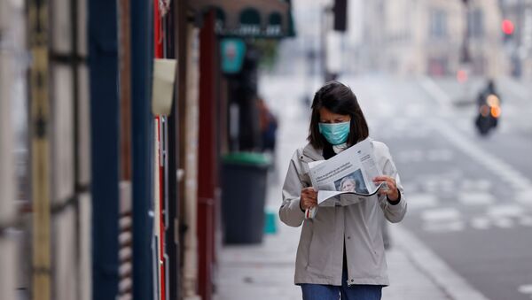 A woman wearing a protective face mask reads a newspaper as she walks in a street on the deserted Ile Saint Louis in Paris as lockdown is imposed to slow the rate of the coronavirus disease (COVID-19) in France, March 18, 2020. - Sputnik International