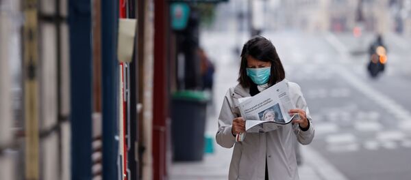 A woman wearing a protective face mask reads a newspaper as she walks in a street on the deserted Ile Saint Louis in Paris as lockdown is imposed to slow the rate of the coronavirus disease (COVID-19) in France, March 18, 2020. - Sputnik International