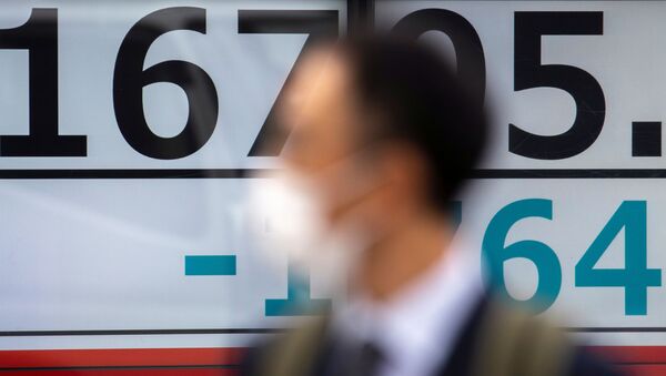 A man wearing a protective face mask, following an outbreak of coronavirus (COVID-19), walks past a screen showing the Nikkei index outside a brokerage in Tokyo, Japan, March 13, 2020 - Sputnik International