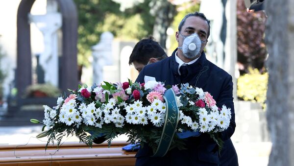 Cemetery workers and funeral agency workers in protective masks transport a coffin of a person who died from coronavirus disease (COVID-19), into a cemetery in Bergamo, Italy March 16, 2020. - Sputnik International