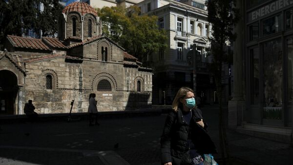 A woman wears a protective face mask as she walks next to a church in Athens, Greece, March 17, 2020. - Sputnik International
