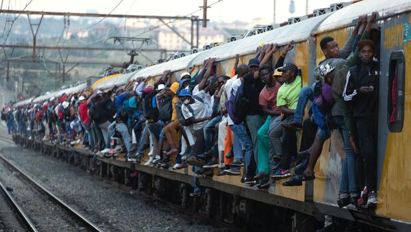  Train commuters hold on to the side of an overcrowded passenger train in Soweto, South Africa, Monday, March 16, 2020. - Sputnik International