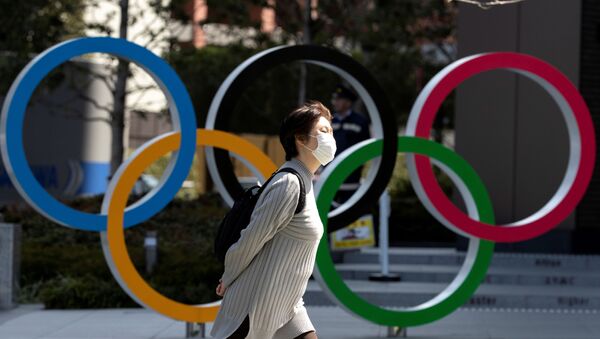 FILE PHOTO: A woman wearing a protective face mask, following an outbreak of the coronavirus disease (COVID-19), walks past the Olympic rings in front of the Japan Olympics Museum in Tokyo, Japan March 13, 2020 - Sputnik International