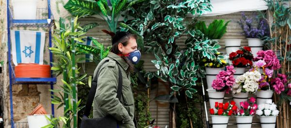A man wears a face mask as he walks in a market in Ashkelon while Israel tightened a national stay-at-home policy following the spread of coronavirus disease (COVID-19) in Ashkelon, Israel March 20, 2020 - Sputnik International
