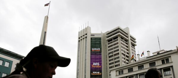 People walk past an electronic sign on the Bolivia's government building displaying the message Stay at home, do it for your family and For my community, as the coronavirus disease (COVID-19) outbreak continues, in downtown La Paz, Bolivia March 20, 2020 - Sputnik International