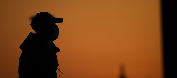 A person wearing a face mask is seen at the sunset as the spread of coronavirus disease (COVID-19) continues, in Milan, Italy March 21, 2020 - Sputnik International