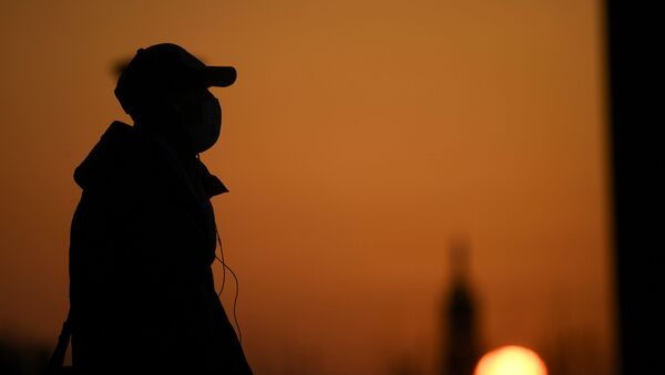 A person wearing a face mask is seen at the sunset as the spread of coronavirus disease (COVID-19) continues, in Milan, Italy March 21, 2020 - Sputnik International