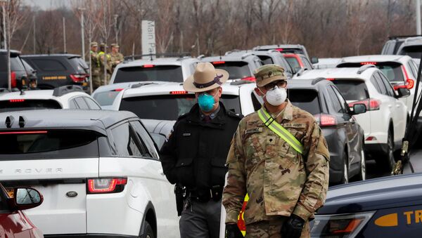 Police and US Military personnel work amid a line of cars of people arriving for testing at a new drive-thru coronavirus disease (COVID-19) testing centre in the Staten Island borough of New York City, 19 March 2020 - Sputnik International