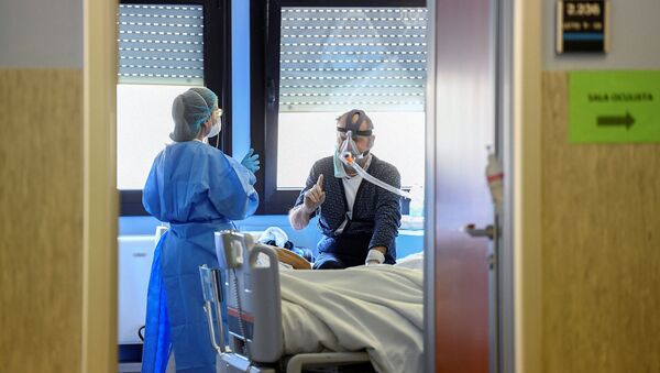 A medical worker wearing a protective mask and suit speaks with a patient suffering from coronavirus disease (COVID-19) in an intensive care unit at the Oglio Po hospital in Cremona, Italy, 19 March 2020.  - Sputnik International