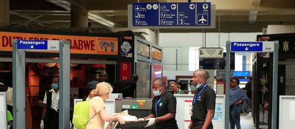 Immigration workers wear protective masks at a departure port at Robert Mugabe International airport in Harare, Zimbabwe, March 11, 2020. Picture taken March 11, 2020. - Sputnik International