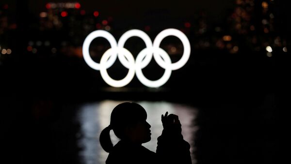 A woman takes a photograph in front of the giant Olympic rings at the waterfront area at Odaiba Marine Park in Tokyo, Japan, March 22, 2020. - Sputnik International