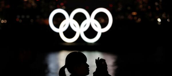 A woman takes a photograph in front of the giant Olympic rings at the waterfront area at Odaiba Marine Park in Tokyo, Japan, March 22, 2020. - Sputnik International