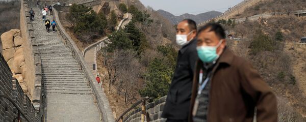 Men wearing protective masks stand as people hike along a section of the Great Wall in Badaling in Beijing, on its first day of re-opening after the scenic site's coronavirus related closure, China, 24 March 2020.  - Sputnik International