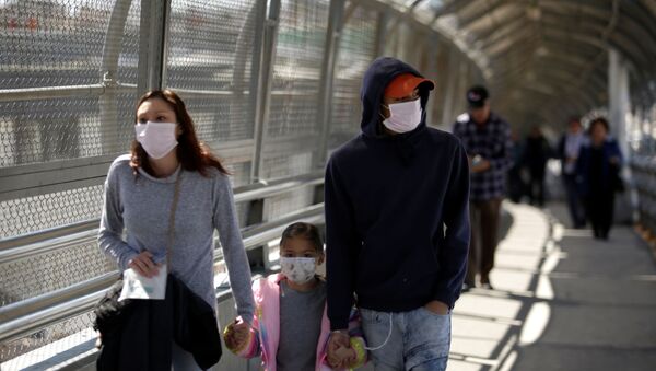 A family wearing protective face masks walks towards the U.S. at the Paso del Norte International Border bridge after the United States and Mexico have agreed to restrict non-essential travel over their shared border in an effort to limit the spread of the new coronavirus (COVID-19), in Ciudad Juarez, Mexico March 20, 2020. - Sputnik International