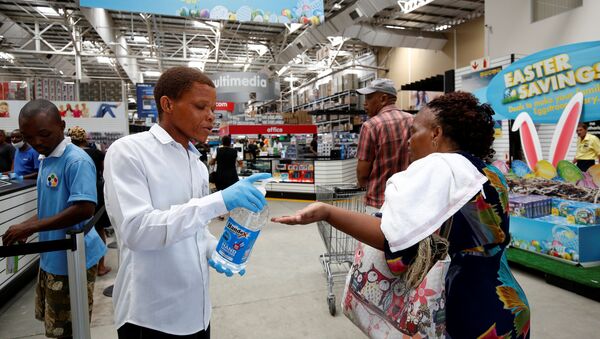 A store assistant gives people hand sanitiser as shoppers stock up on groceries at a Makro Store ahead of a nationwide 21 day lockdown in an attempt to contain the coronavirus disease (COVID-19) outbreak in Durban, South Africa, March 24, 2020. - Sputnik International