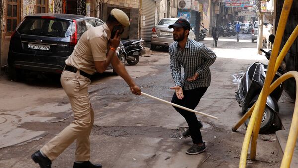 A police officer wields his baton against a man as a punishment for breaking the lockdown rules after India ordered a 21-day nationwide lockdown to limit the spreading of coronavirus disease (COVID-19), in New Delhi, India, March 25, 2020 - Sputnik International