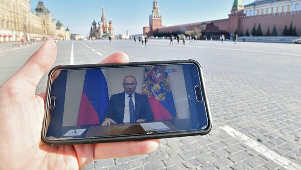 A Moscow resident is in Red Square watching a broadcast of Russian President Vladimir Putin's address on the government's coronavirus response - Sputnik International