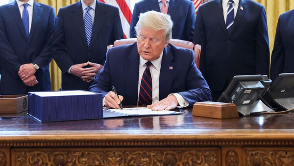 U.S. President Donald Trump signs the $2.2 trillion coronavirus aid package bill as he sits at the Resolute Desk in the Oval Office of the White House in Washington, U.S., March 27, 2020. - Sputnik International