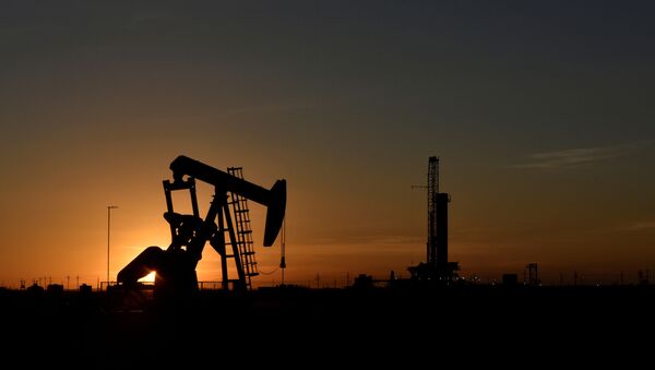FILE PHOTO: A pump jack operates in front of a drilling rig at sunset in an oil field in Midland, Texas U.S. August 22, 2018. Picture taken August 22, 2018. - Sputnik International