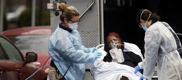 Emergency Medical Technicians (EMT) wearing protective gears wheel a sick patient to a waiting ambulance during the outbreak of coronavirus disease (COVID-19) in New York City, New York, U.S. - Sputnik International
