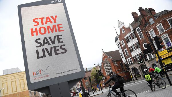 Cyclists pass an electronic billboard displaying a Public health information campaign message from the UK government and local government in London as the spread of the coronavirus disease (COVID-19) continues, London, Britain, March 28, 2020. - Sputnik International