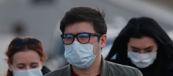 People wearing protective masks walk near a hospital for patients infected with coronavirus disease (COVID-19) on the outskirts of Moscow, Russia March 23, 2020. - Sputnik International