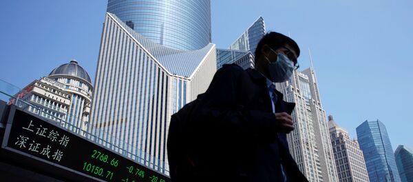 A pedestrian wearing a face mask walks near an overpass with an electronic board showing stock information, following an outbreak of the coronavirus disease (COVID-19), at Lujiazui financial district in Shanghai, China March 17, 2020.  - Sputnik International