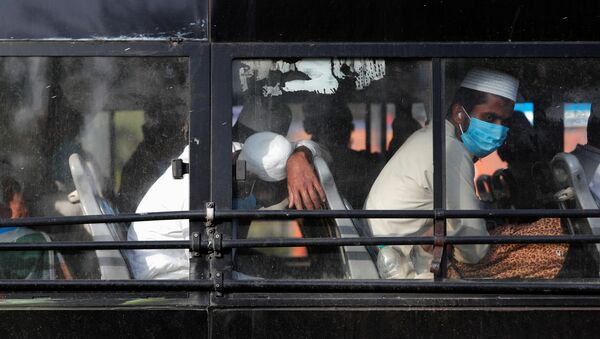 Men wearing protective masks sit inside a bus that will take them to a quarantine facility, amid concerns about the spread of coronavirus disease (COVID-19), in Nizamuddin area of New Delhi, India, March 31, 2020 - Sputnik International