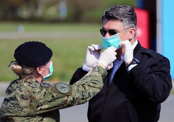 A soldier helps Croatia's President Zoran Milanovic to wear a face mask before he visits the tents which are built for patients who will have coronavirus disease (COVID-19) at Dubrava hospital in Zagreb, Croatia, March 21, 2020.  - Sputnik International